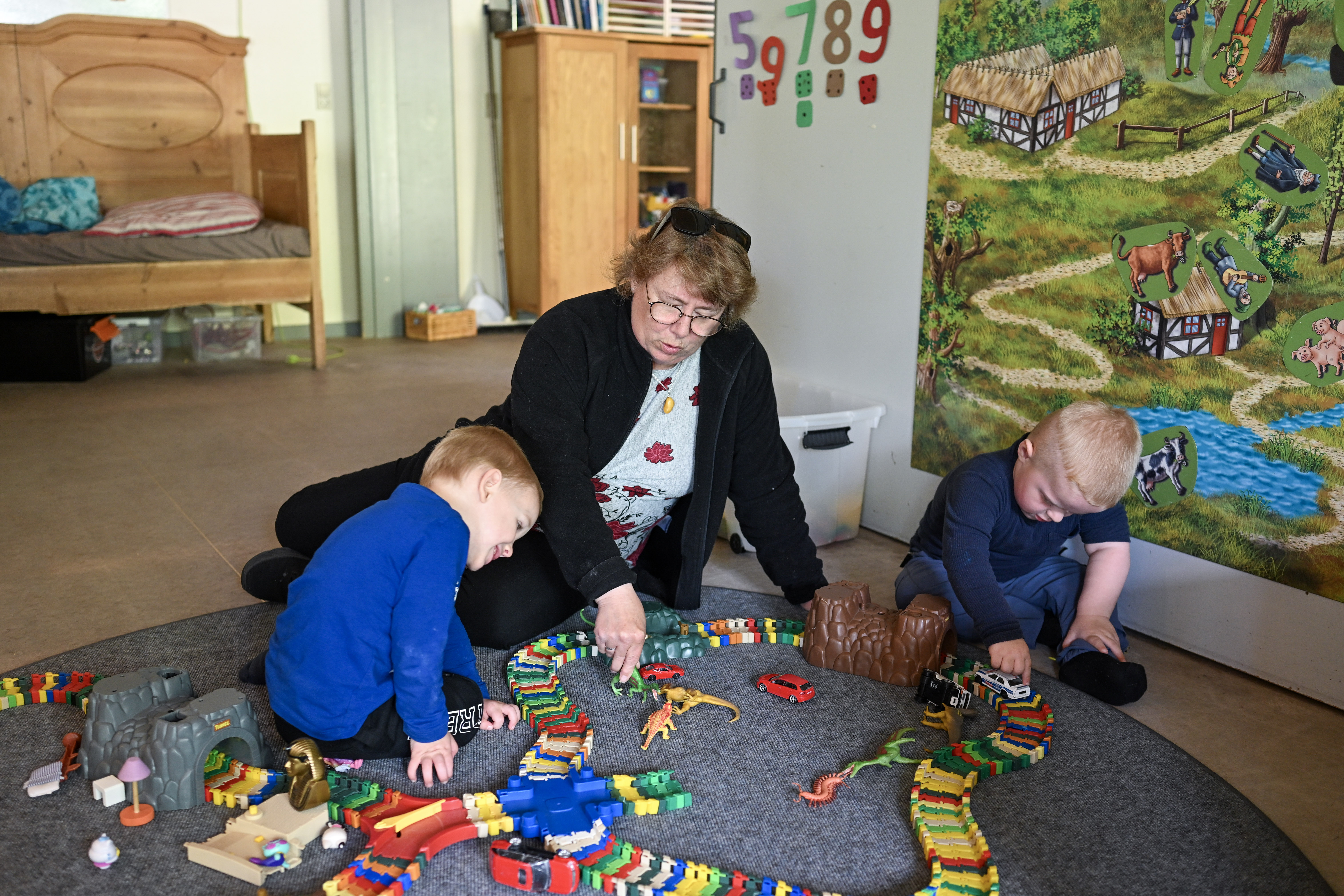 Børn og voksen leger med biler og dinosaurer